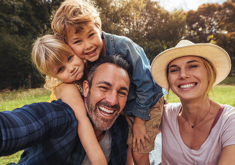 Family of four smiling outside