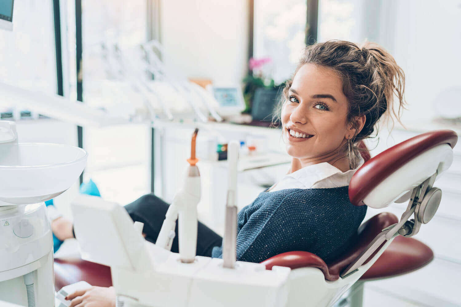 Brunette woman in a dental chair smiles while at her dentist in Wolcott, CT