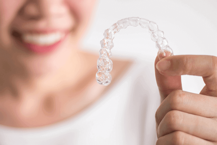 woman holding up an invisalign aligner