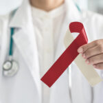 A dentist holds a red and beige ribbon for oral cancer awareness
