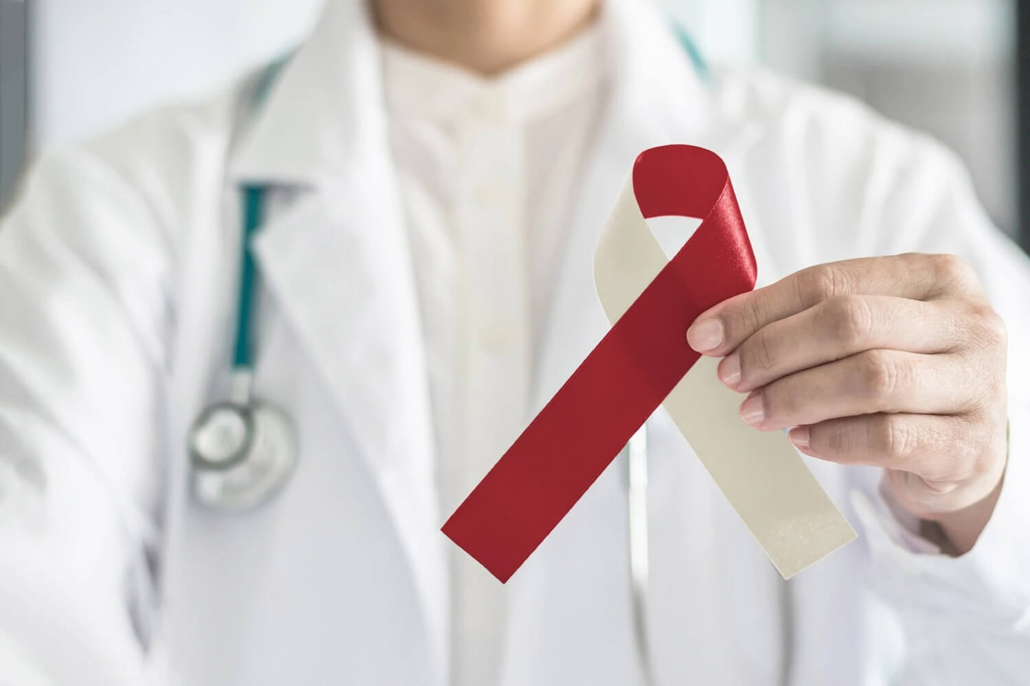 A dentist holds a red and beige ribbon for oral cancer awareness