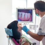 Male dentist examining a brunette woman's teeth using an intraoral camera