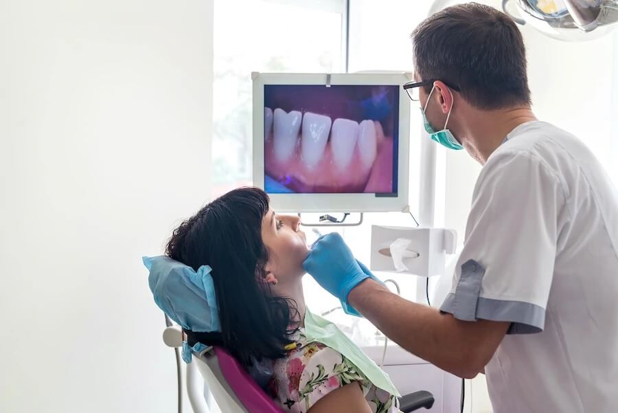 Male dentist examining a brunette woman's teeth using an intraoral camera