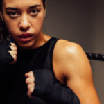 closeup of a female boxer in fighter stance participating in martial arts with a sports mouthguard and wraps on her hands
