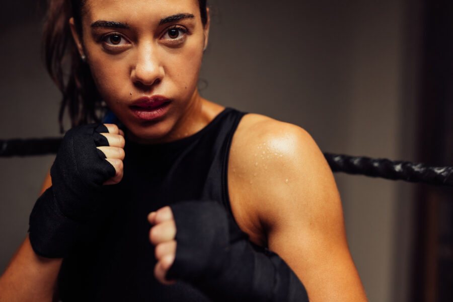 closeup of a female boxer in fighter stance participating in martial arts with a sports mouthguard and wraps on her hands