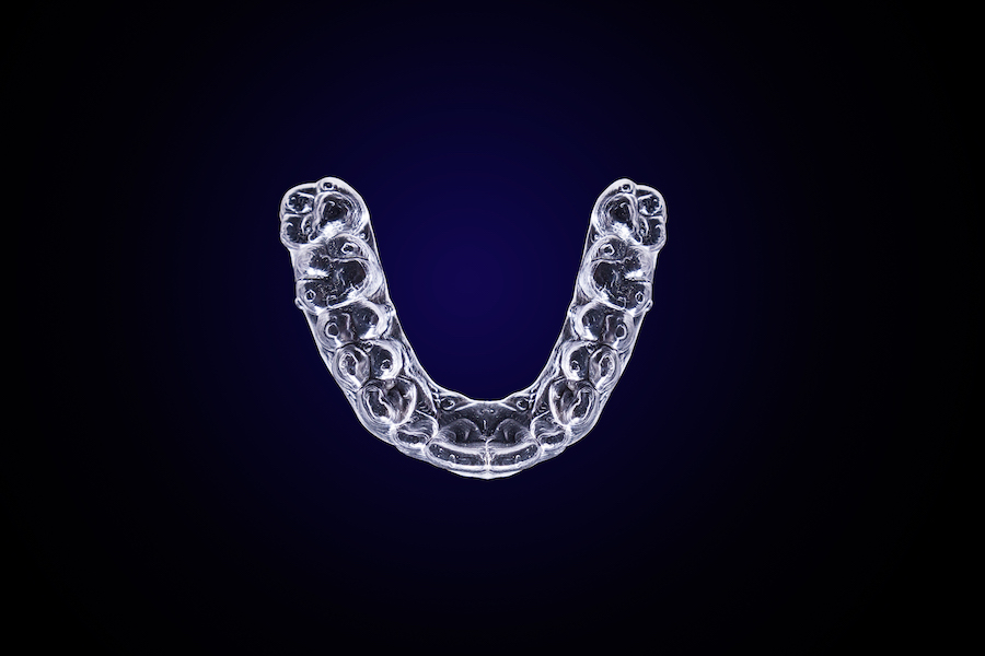 Aerial view of clear aligners on a dark blue background