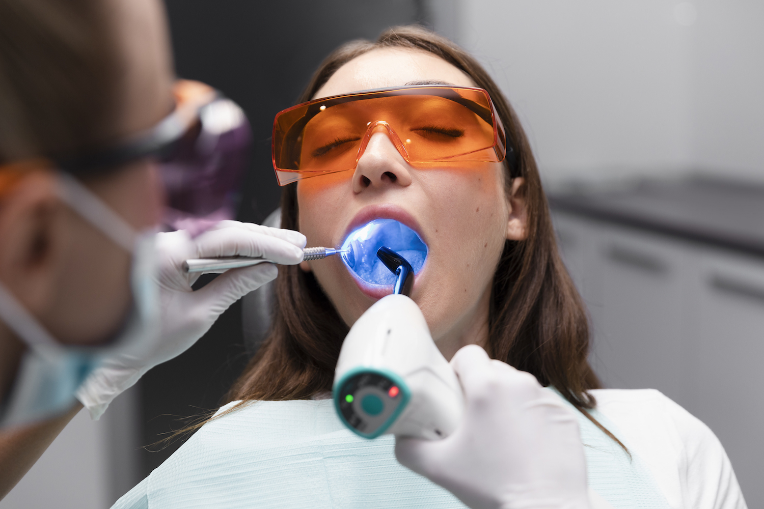 Image of woman in dental chair receiving a preventive oral cancer screening with a specialized light.