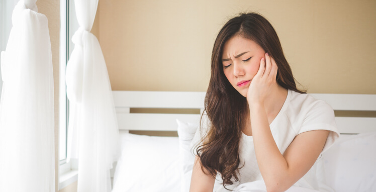 woman holding her jaw in pain